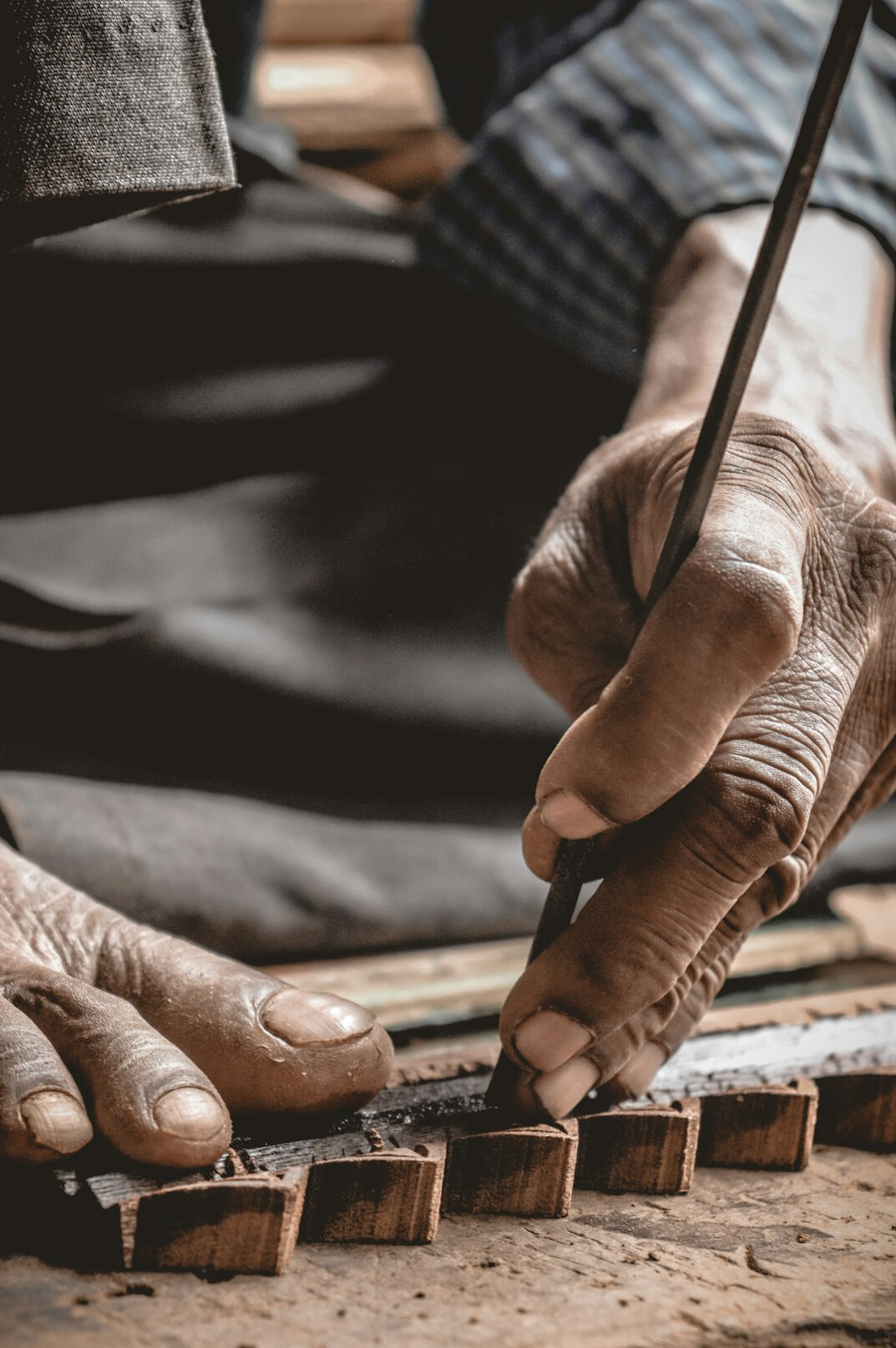 Close-up of an elderly craftsman's hands working with tools